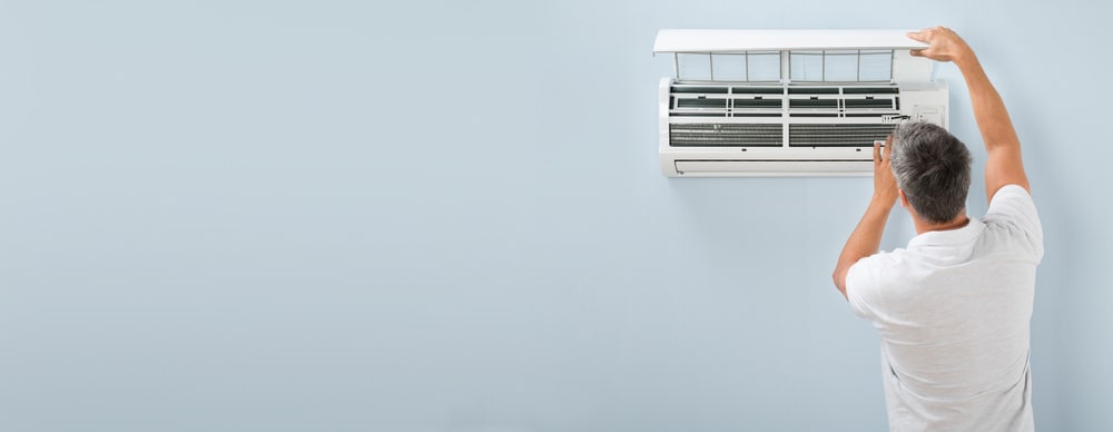 A Man Looking At The Inside Of His Air Conditioner